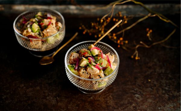 Two glass bowls of Japanese style ceviche with avocado and radish, served with gold spoons.
